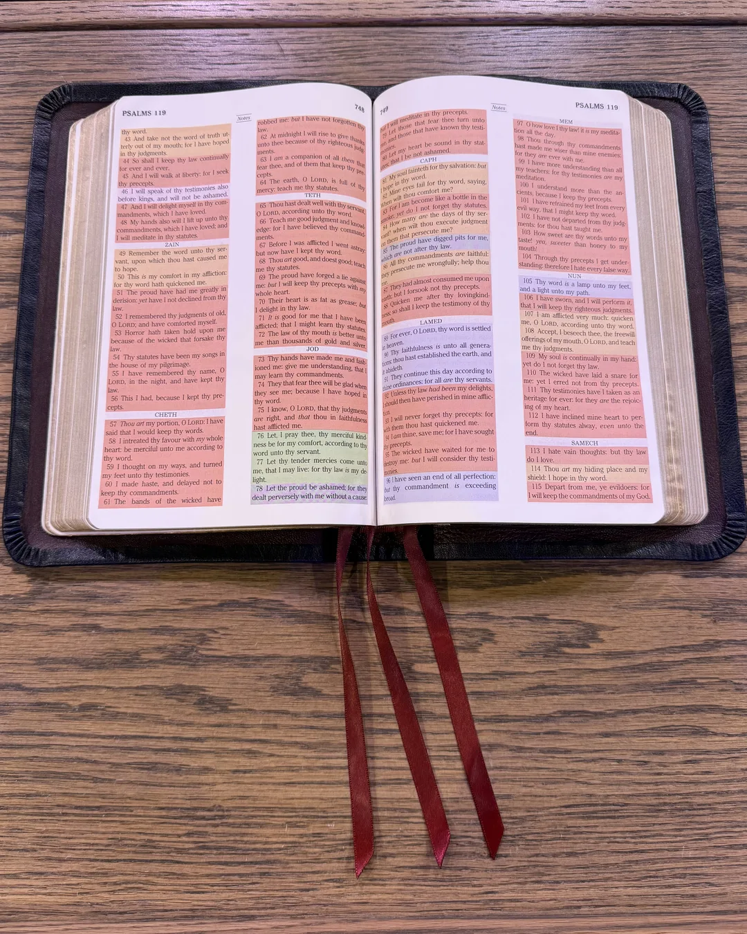 Open Bible with highlighted pages and red ribbons, leather edge visible